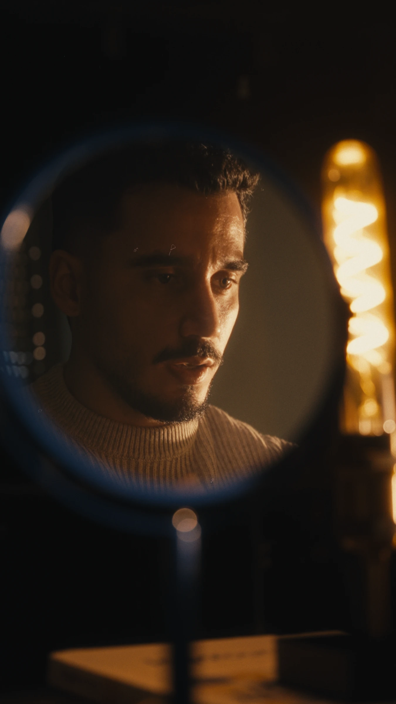 Sam Hox seen in a round mirror at the desk