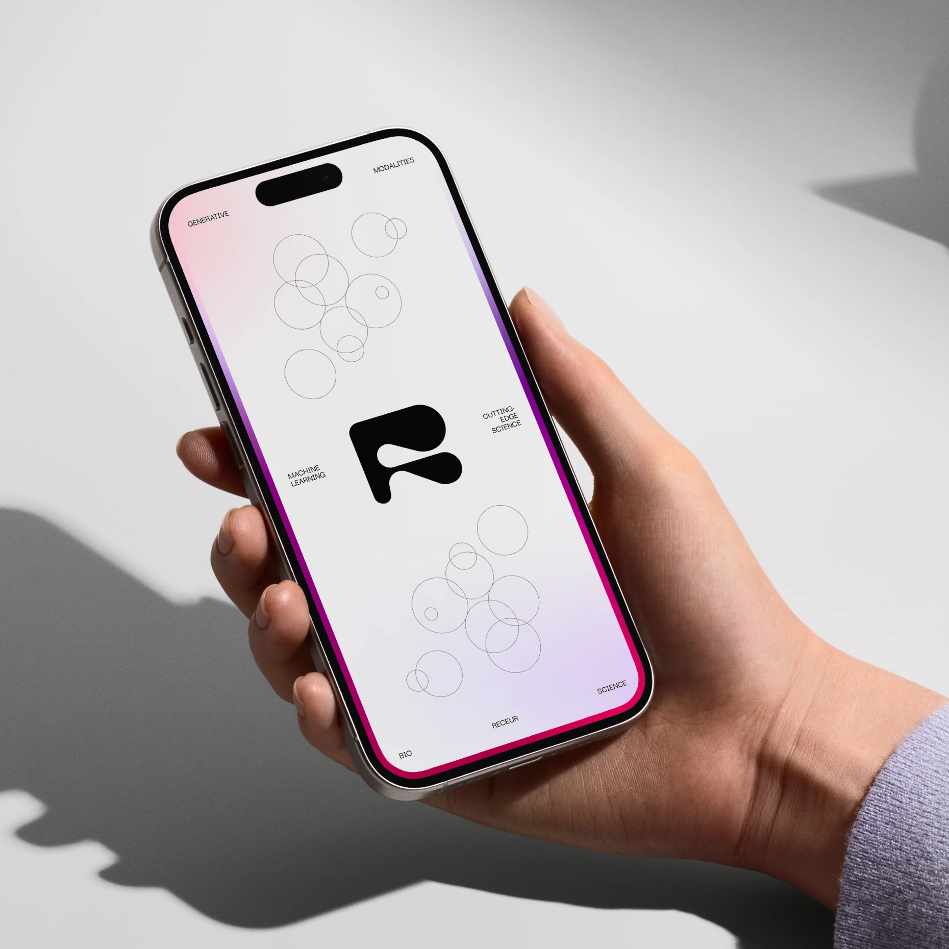 Hand holding a phone showing the black Receur R mark among outlined circles